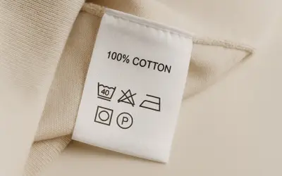 Metka z 100% bawełny. Zawiera skróty tkanin i symbole pielęgnacji: pranie w 40°C, zakaz wybielania, prasowanie, suszenie w suszarce i czyszczenie chemiczne.