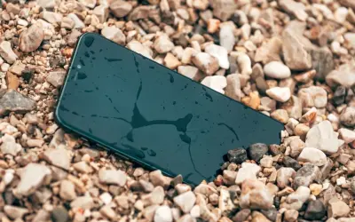 Smartfon leży na kamieniach, mokry, ale wytrzymały zgodnie ze **standardem militarnym MIL-STD-810H**.