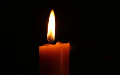 Płonąca pomarańczowa świeca. Jej ciepłe światło symbolizuje nadzieję i radość, rozpraszając mrok.