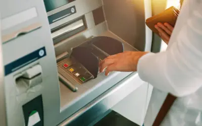 Dłoń wpisuje PIN przy bankomacie, z nadzieją, że nie zniknęły pieniądze z konta.