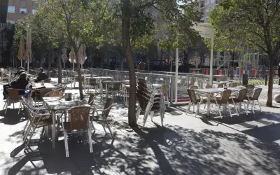 Mesas y sillas vacías en la terraza de bares de la plaza San Francisco, bajo la sombra de los árboles.