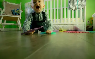 Wesołe dziecko kiedy dziecko raczkuje, bawi się kolorowymi puzzlami na podłodze w pokoju dziecięcym.