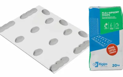 Płyta gipsowo-kartonowa z fazowaniem, obok worek kleju gipsowego Rigips.