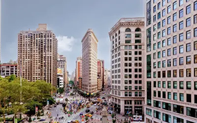 Vista aérea de Nueva York con el icónico edificio Flatiron en el centro. Los planos de la ciudad muestran la intersección de calles y la arquitectura circundante.