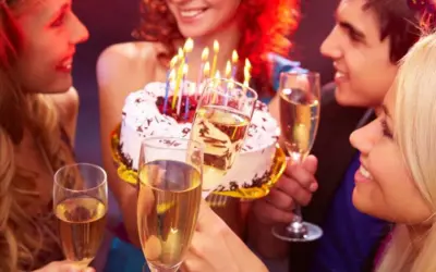 Amigos celebran con pastel y copas de champán. ¡Así se escribe happy birthday en español: ¡Feliz Cumpleaños!