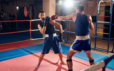 Two boxers spar in a ring, one throwing a punch combo as the other dodges.