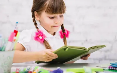 Dziewczynka z warkoczami czyta książkę, marząc o przyszłości, gdy zdobędzie kurs pedagogiczny uprawniający do pracy w szkole.