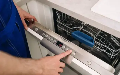 Ręka naciska przycisk na panelu zmywarki Whirlpool, pokazując, jak zresetować zmywarkę Whirlpool.