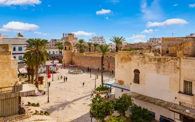 Tunezja Sousse czy warto? Rynek z palmami, zabytkową wieżą i flagami. Słoneczny dzień zachęca do zwiedzania.