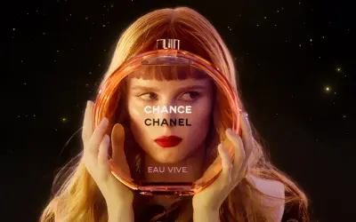 Kobieta z rudymi włosami trzyma okrągłą butelkę perfum Chanel Chance Eau Vive.