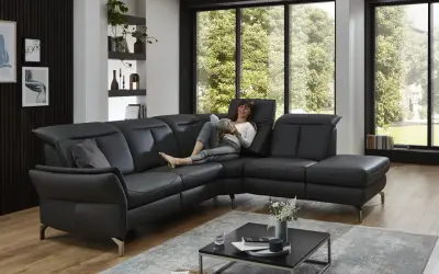 Frau liest auf schwarzem Ledersofa. Dieses Leder ist am robustesten und pflegeleicht, ideal für den Alltag.