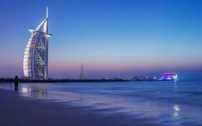 Wieczór w Dubaju. Luksusowy hotel Burdż al-Arab i oświetlony statek na morzu. Ceny w Dubaju mogą być wysokie, ale widoki są niezapomniane.