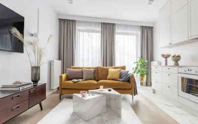 Musztardowa kanapa inspiracje: przytulny salon z nowoczesną kuchnią. Miękkie poduszki i pled dodają ciepła.