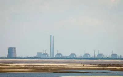 Widok na elektrownię Zaporoże z chłodnią kominową i kilkoma blokami energetycznymi na tle nieba.