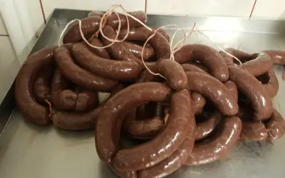 Kaszanka, pyszna i tradycyjna, idealna dla dzieci. Wiele krążków świeżej kaszanki na metalowej tacy.