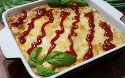 Pyszne, zapieczone fit lasagne w białym naczyniu, polane ketchupem i ozdobione listkami bazylii.