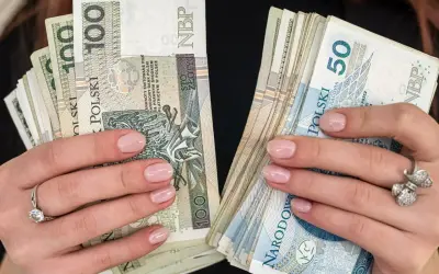 Dłonie z paznokciami pomalowanymi na jasny róż trzymają stosy polskich złotówek. W jednej ręce banknoty 100 zł, w drugiej 50 zł. To pewnie babciowe na drobne wydatki.