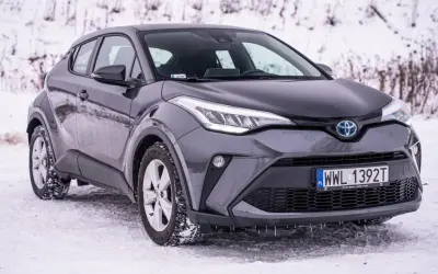 Szara, używana Toyota C-HR na śniegu. Stylowy crossover gotowy na zimowe wyzwania.