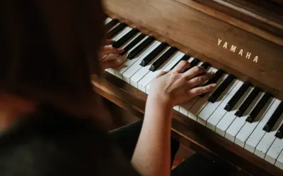 Dłonie dorosłego ćwiczą naukę gry na pianinie Yamaha.