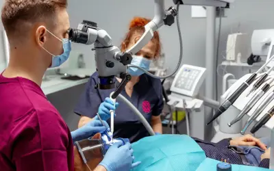 Stomatolog z mikroskopem precyzyjnie usuwa próchnicę z zęba pacjenta.