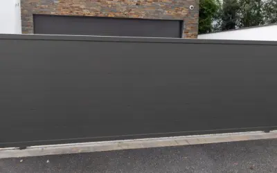 Nowy, nowoczesny montaż bramy przesuwnej w kolorze grafitowym, idealnie komponuje się z kamienną elewacją domu.