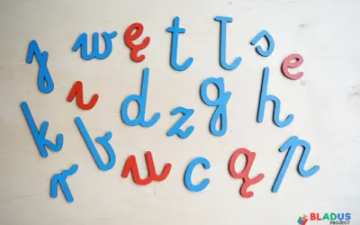Drewniane litery alfabetu łacińskiego w kolorach niebieskim i czerwonym, ułożone na drewnianym tle.
