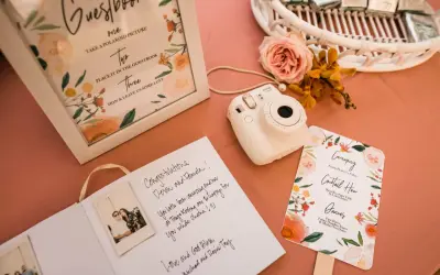 Wpis do księgi gości z polaroidami i życzeniami. Aparat Instax czeka na uwiecznienie chwil.