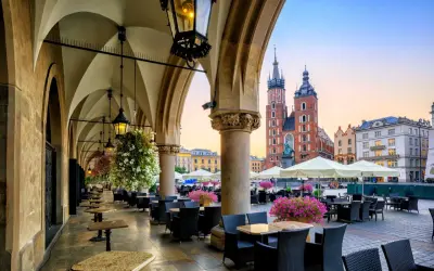 Krakowskie Sukiennice, co to? To historyczne miejsce z kawiarnianymi stolikami i widokiem na Kościół Mariacki.