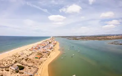 Faro: Was tun? Eine Küstenstadt mit Sandstrand, Häusern und vielen Booten im Wasser. Perfekt für einen entspannten Urlaub.