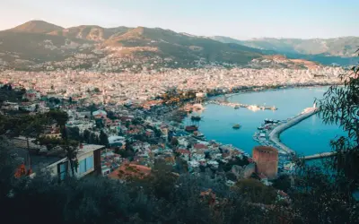 Widok na zatokę i miasto Alanya, z górami w tle. Widać port z łodziami i charakterystyczną czerwoną wieżę, część historycznego Alanya stare miasto.