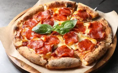 En napolitansk pizza med generöst med pepperoni som topping, toppad med färsk basilika.