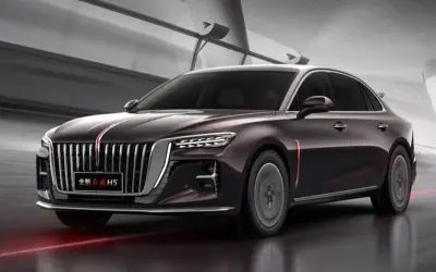 Elegancki, ciemnofioletowy Hongqi H5 z charakterystycznym grillem i czerwonym pasem na masce, poruszający się po nowoczesnej drodze.