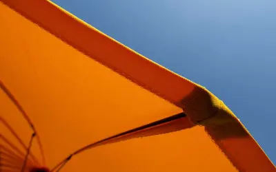 Orange Sonnenschirm-Stoff mit Baumwolle für UV-Schutz vor blauem Himmel.