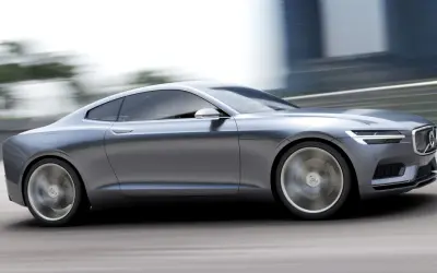 Eleganckie, szare volvo coupe pędzi po drodze, rozmywając tło.