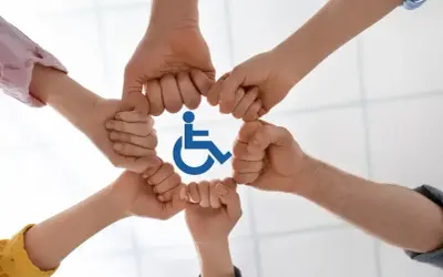 Dłonie tworzą krąg wokół symbolu niepełnosprawności, symbolizując wsparcie i integrację.