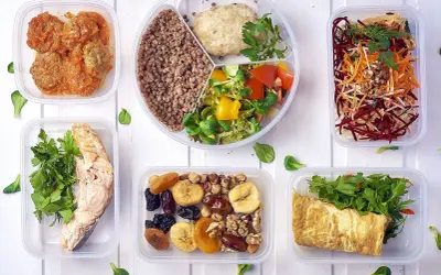 Pyszny, bezglutenowy jadłospis w pojemnikach: łosoś, kotleciki, kasza, sałatka, omlet, owoce i orzechy.
