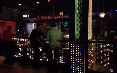 Leute sitzen an einer Bar in Stuttgart, die mit bunten Lichtern beleuchtet ist. Ein gemütlicher Abend im Oblomow.