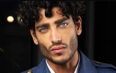 Uomo con capelli mossi scuri e occhi azzurri penetranti, un look che ispira su come farsi i capelli mossi uomo.