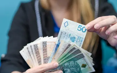 Dłoń trzyma plik polskich banknotów: 50, 100 i 200 zł. Może to być oferta kredytu w Revolut.