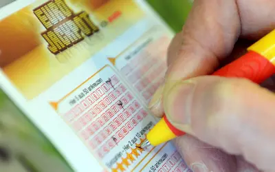 Prawda o rzekomych wróżbitach, którzy trafili liczby w Eurojackpot. Dłoń zaznacza liczby na kuponie lotto.