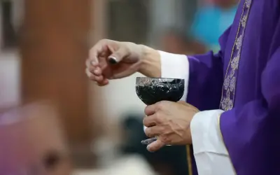 Dłoń księdza w purpurowej szacie trzyma kielich z winem. Dziś, 15 lutego, trwa ważna ceremonia.