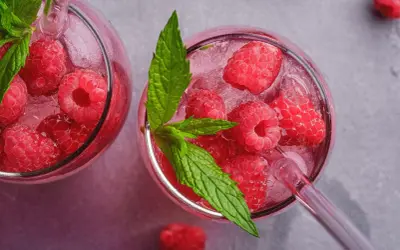 Orzeźwiająca lemoniada malinowa z lodem i listkami mięty w szklanych kieliszkach.