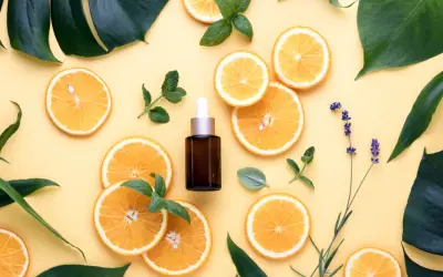 Siero viso con niacinamide e vitamina c, circondato da fette d'arancia, foglie verdi e lavanda.