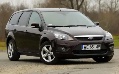Ciemnobrązowy Ford Focus MK2 1.6 TDCI kombi stoi na szutrowej drodze.