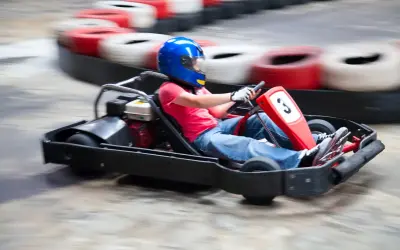 Dziecko w niebieskim kasku śmiga gokartem po torze w Warszawie. Emocjonująca jazda gokartami dla dzieci.