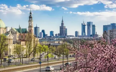 Majówka w Warszawie: zabytkowy kościół i nowoczesne wieżowce na tle kwitnącej wiśni.