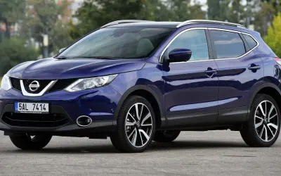 Granatowy Nissan Qashqai 2016 z chromowanymi relingami dachowymi i felgami.