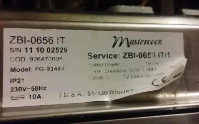 Naklejka z danymi technicznymi kuchenki Mastercook ZBI-0656 IT. Znajdziesz tu m.in. numer seryjny, model FG-9348A, moc 1950W, ciśnienie wody 0.04-1.00M, pojemność 12 kompletów.