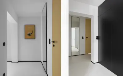 Minimalistyczny, mały przedpokój inspiracje ściany: złote i czarne drzwi, lustro, grafika z fotelem Eamesa.