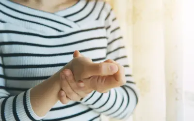 Frau hält ihren Daumen, der schmerzt, als ob sie einen Schnappfinger Daumen hätte.